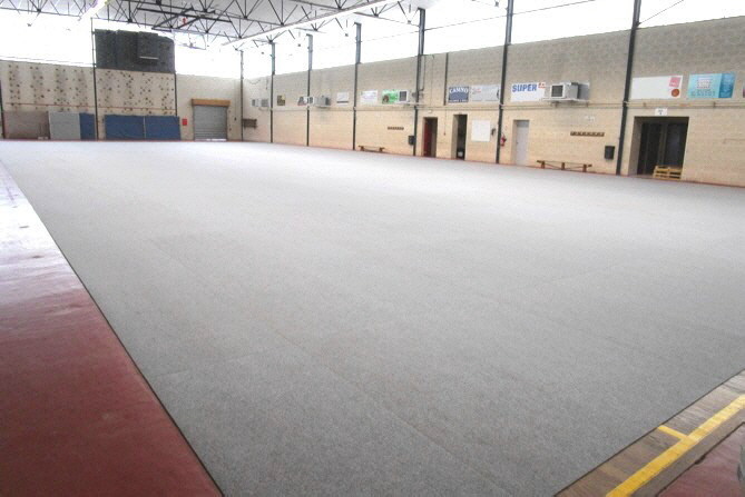 Sport- und Turnhalle mit geschütztem Sportbodenbelag durch Teppichfliesen Typ CONCORD aus Nadelfilz und rutschhemmender Unterseite