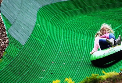 Kind im Reifen rutschend auf der Tubing Bahn